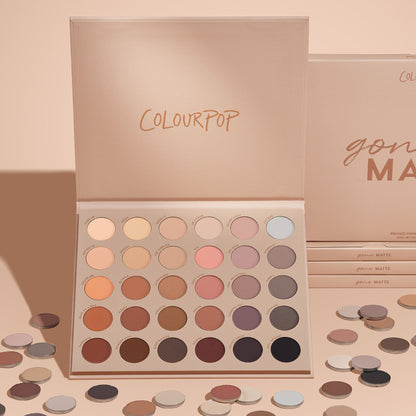 ColourPop Gone Matte shadow palette displaying 30 matte neutral eyeshadows - from ivory and taupe to rose, mauve, terracotta, chocolate, and black - open on a blush-beige backdrop with scattered single pans and stacked boxes.