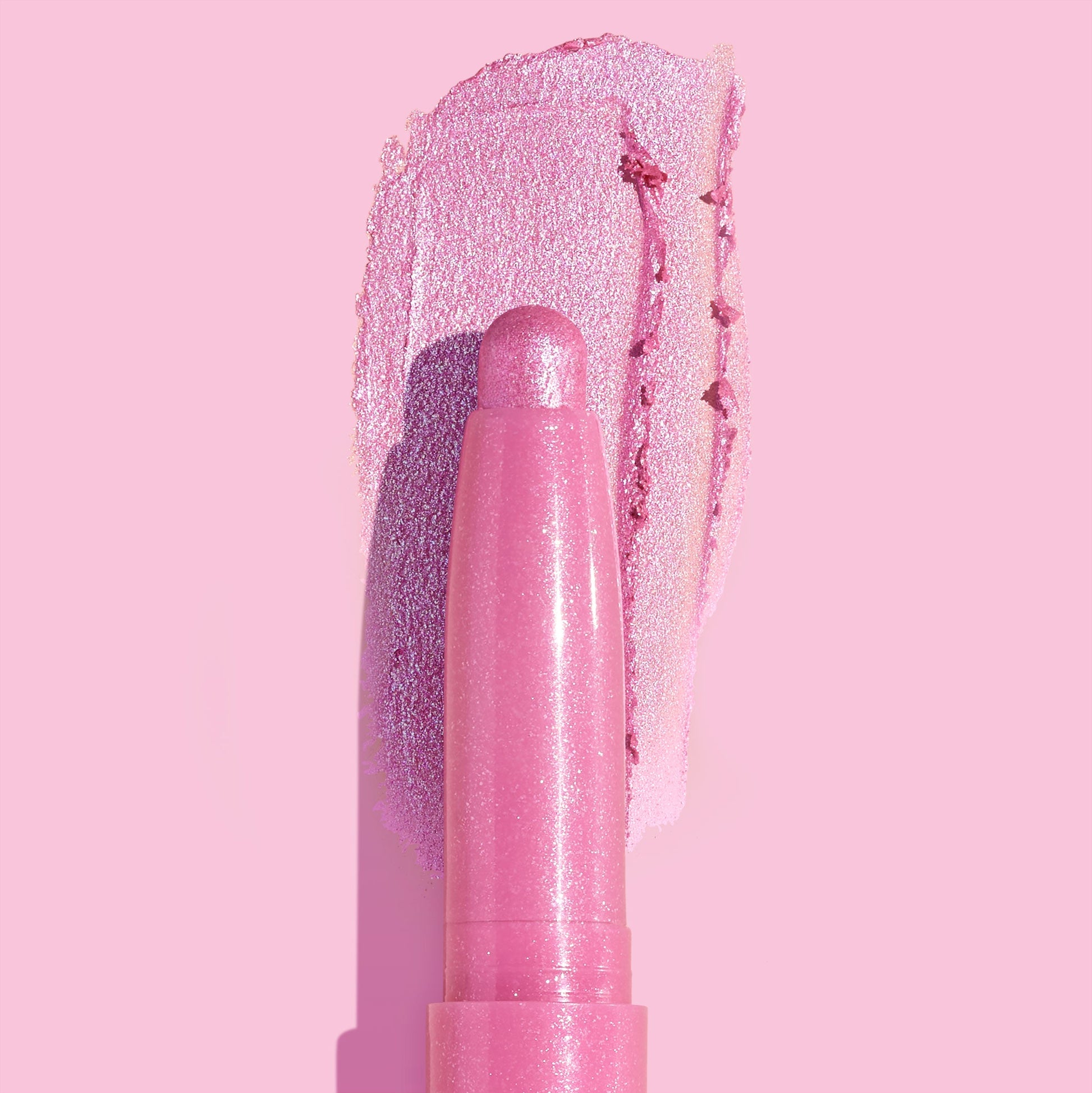 Juicy Gossip Shadow Stix glides a metallic bubblegum-pink swatch across a pastel pink background, showcasing the creamy, shimmery payoff of the ColourPop Shadow Stix twist-up eyeshadow stick.