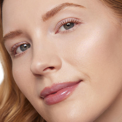Softly lit cheekbone catching light, showcasing ColourPop Liquid Highlighter in Mother Gothel, a liquid highlighter with a pearly iridescent glow applied on light skin in a close-up beauty shot with a dewy, glassy finish.
