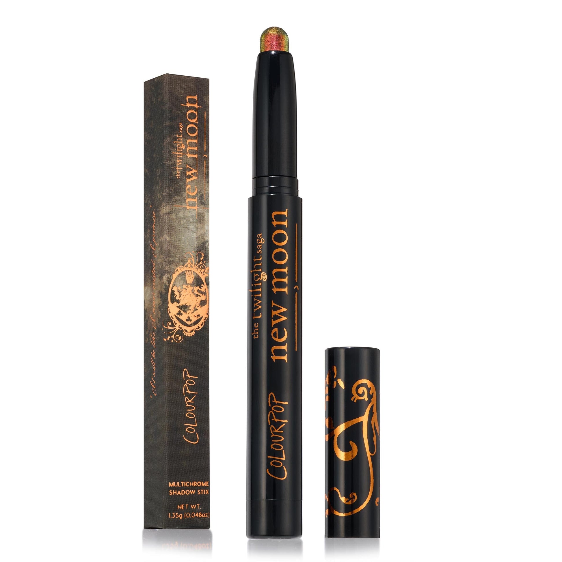 Vampire Girl ColourPop Shadow Stix stands uncapped, revealing a multichrome green-to-red shimmer tip, with its black cap and matching New Moon Twilight collab box beside it, both in black with copper-gold graphics, on a white backdrop.