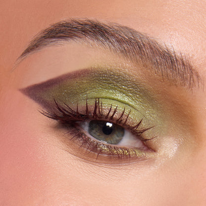 Close-up eye wearing shimmering ogre-green, olive, and chartreuse shadow with a sharp plum cut crease and lengthened lashes, showcasing the Shrek-Spress Yourself ColourPop Lip and Eye Set for bold green glam looks.